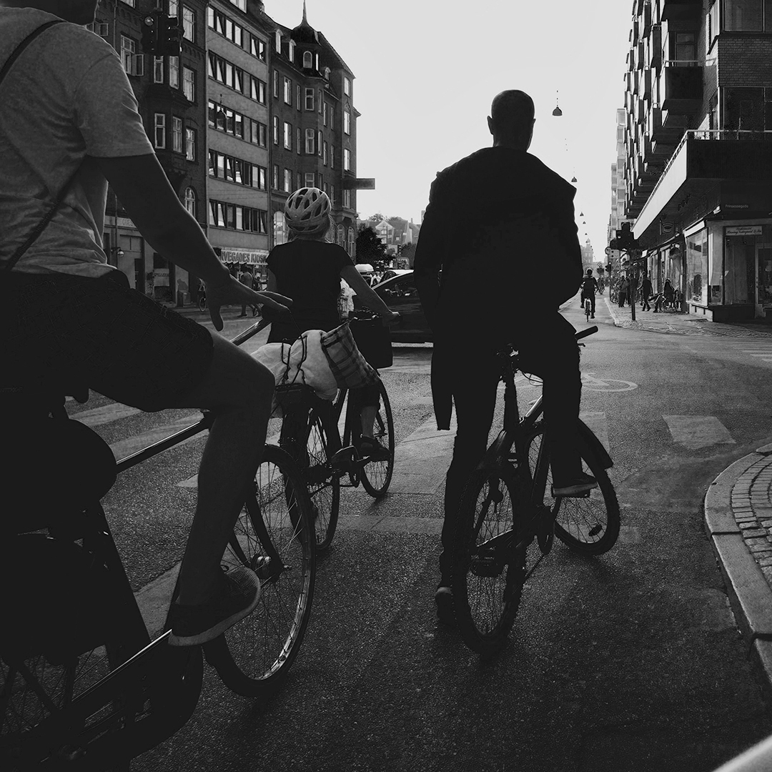 Ciclistas de costas parados nunha rúa en blanco y negro cuadrado